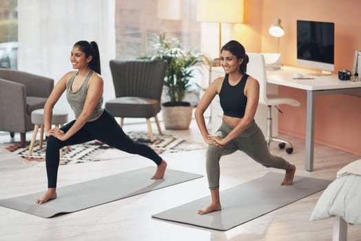Women, yoga and friends exercise in a house together with smile, health and wellness. Indian sisters or female family in a lounge while happy about workout, stretching and fitness with a partner.