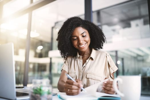 Starting up a new project. a young businesswoman writing notes at her desk in a modern office