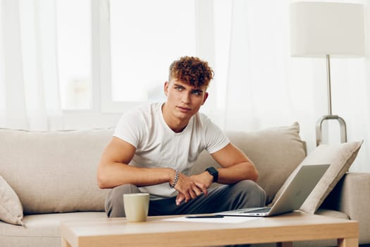 man interior lifestyle computer browsing cyberspace t-shirt cup education happy home looking indoor modern typing sitting chat