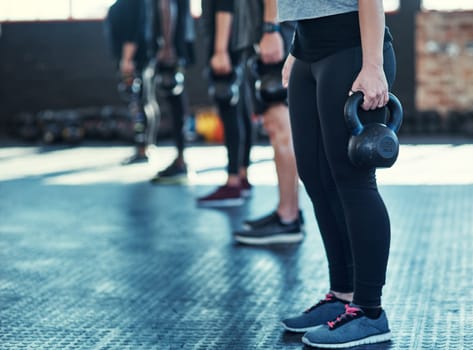 Weights for strength. a group unrecognizable people standing in a row doing training with weights in a gym