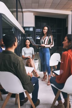 Working together is a success. a young businesswoman holding her laptop while giving a business presentation