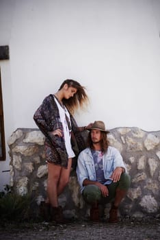 Hipster fashion done right. a trendy young couple standing together against the wall of a building outside
