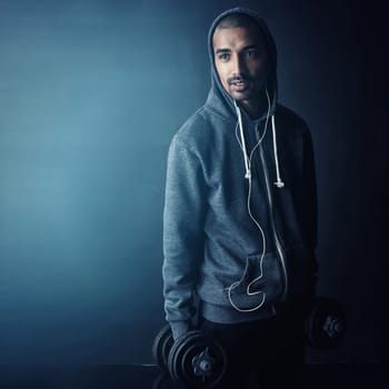 Always lifting. Studio shot of a young man working out against a dark background