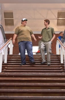 Student, teenager friends and campus boys walking down university and school steps with a smile. Conversation, talking and discussion of guy group feeling happy on education building stairs with talk.