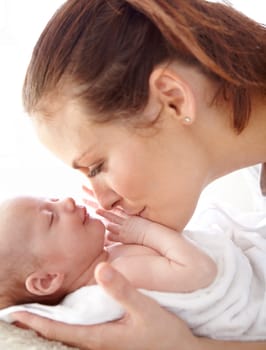 Mother, kiss and newborn baby in closeup with love, happiness and care in bedroom at family home. Young mom, infant child and hug with happy bonding, pride and together on bed in morning at house.