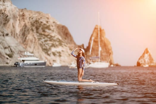 Woman sup yoga. Middle age sporty woman practising yoga pilates on paddle sup surfboard. Female stretching doing workout on sea water. Modern individual hipster outdoor summer sport activity