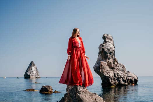 Woman travel sea. Happy tourist taking picture outdoors for memories. Woman traveler looks at the edge of the cliff on the sea bay of mountains, sharing travel adventure journey.