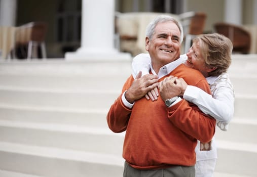 Hug, retirement and an old couple on hotel steps for travel, vacation or tourism in luxury accommodation. Love, relax or hospitality with a senior man and woman hugging on the staircase of a resort.