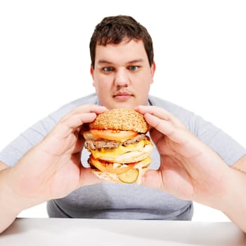 Plus sized, eating and man holding burger, unhealthy diet and isolated hungry person and white background. Junk food, weight loss and healthcare problem, male with bad food addiction in studio