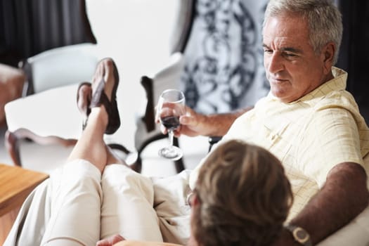 Relax, love and an old couple drinking wine in their hotel room while on holiday or vacation together. Toast, sofa or retirement with a senior man and woman bonding at a luxury resort for romance.