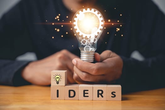 Question and solution concept. Person holding wooden block with light bulb icon, suggesting an answer with copy space. Innovation and problem-solving for corporate success. new ideas