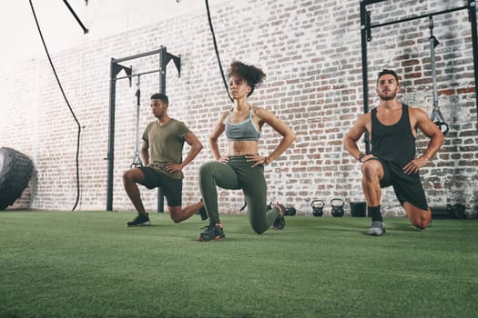 Doing it together is what keeps us motivated. a fitness group doing lunges while working out at the gym