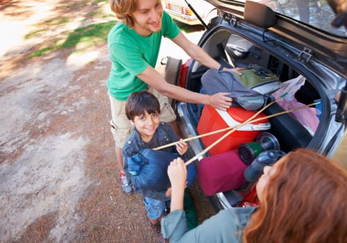Happy family, road trip and packing car trunk for camping, holiday or vacation above in nature outdoors. Top view of dad or kids getting ready for travel, camp adventure or getaway together in forest.