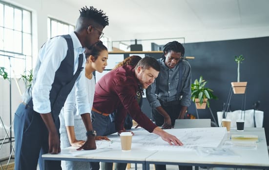 Being careful about detail. a team of professionals working on blueprints in an office