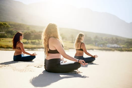 Clear your mind. three young women practising yoga on the beach