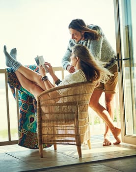 Their weekend is booked for relaxation. a young couple reading a book together while relaxing on the balcony