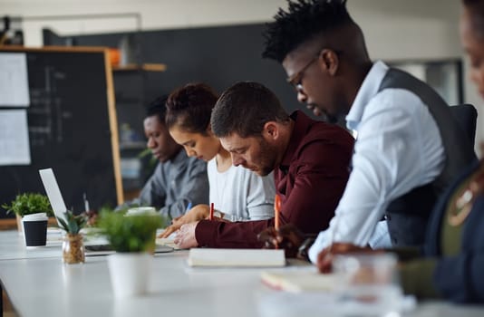 Getting down to work. a group of businesspeople listening to a presentation in an office