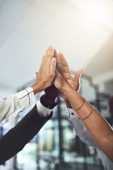 Were here to become winners. Closeup shot of a group of businesspeople giving each other a high five in an office