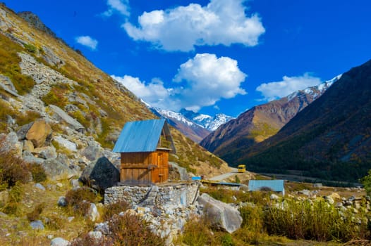 A small cabin room in a mountain valley against blue sky and flying clouds in the background. Chitkul Village Himachal Pradesh India South Asia Pacific