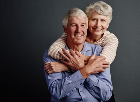 Ill never let him go. Studio portrait of an affectionate senior couple posing against a grey background