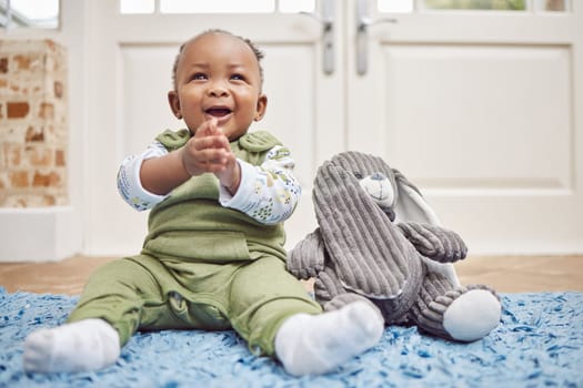 Smile, baby and black child clapping in home, having fun or enjoying teddy bear. African newborn, children and toddler, kid and young infant play, happy or applause for childhood development in house.