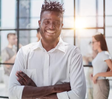 Portrait of smiling African American business man with executives working on laptop in background.