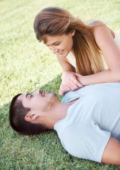 Relaxing outdoors together. An attractive young couple lying on the grass together and smiling