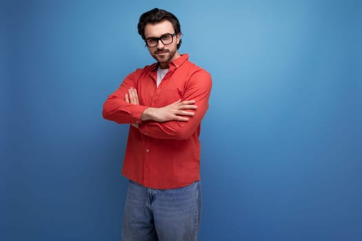 confident stylish 35 year old brunette millennial man with gorgeous hair in a red shirt on a studio background with copy space.