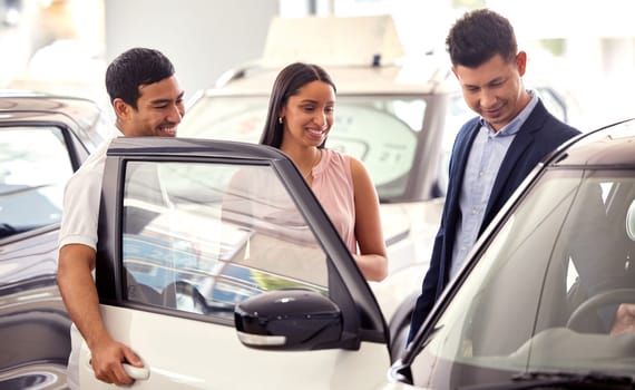 Couple at car dealership, choice and transport with salesman, people buying new transportation with luxury. Happy with decision, man and woman at automobile showroom with purchase and browsing cars.