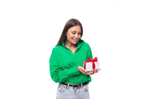 cute young brown-eyed brown-haired woman with makeup in a green blouse decides to prepare a gift for her boyfriend's holiday.