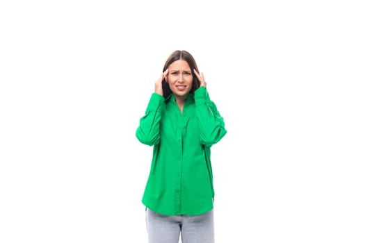 attractive confused young caucasian brunette lady with make-up dressed in an elegant green shirt on a white background with copy space.