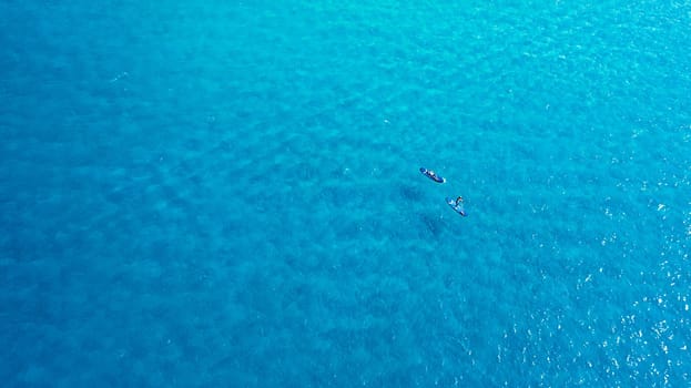 Explore the waters on a paddle boat. a man and woman paddle boarding across the sea