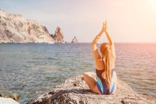 Woman sea yoga. Back view of free calm happy satisfied woman with long hair standing on top rock with yoga position against of sky by the sea. Healthy lifestyle outdoors in nature, fitness concept.