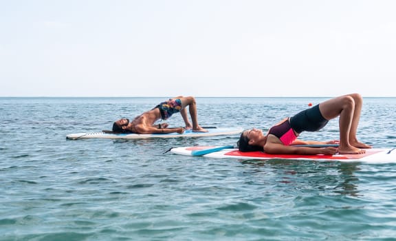 Woman man sup yoga. Happy young sporty couple practising yoga pilates on paddle sup surfboard. Female stretching doing workout on sea water. Modern family outdoor summer sport activity