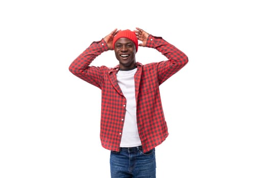 portrait of handsome 30s black american man dressed in red shirt and cap on white studio background with copy space.