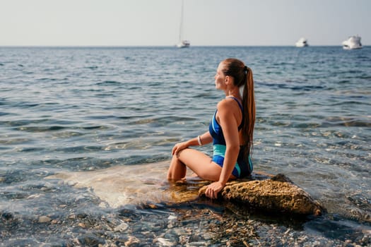 Woman travel sea. Young Happy woman in a long red dress posing on a beach near the sea on background of volcanic rocks, like in Iceland, sharing travel adventure journey