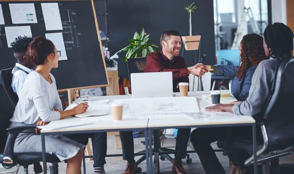 I know youre going to bring a lot to this team. two creative businesspeople shaking hands during a meeting in their office