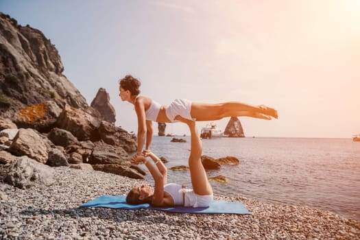 Woman sea yoga. Back view of free calm happy satisfied woman with long hair standing on top rock with yoga position against of sky by the sea. Healthy lifestyle outdoors in nature, fitness concept.