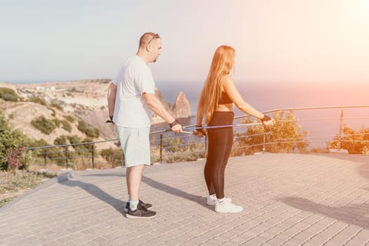 Happy Middle aged couple or friends practicing nordic walking in park near sea. Mature couple with trekking poles walking, practicing Nordic walking outdoors. Aging youthfully and sport concept.