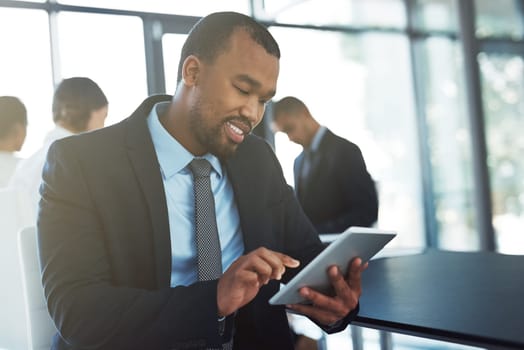 An essential tool for executives. a young businessman using a digital tablet during a meeting at work