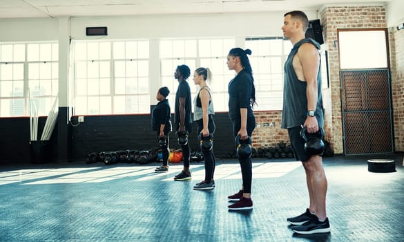 Stay as you are. a focused group of young people standing in a row and training with weights in a gym