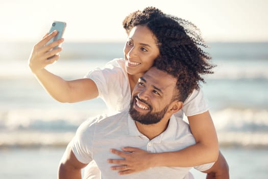 Couple, piggyback and selfie at beach, smile and happy on holiday with summer sunshine for blog, post and web. Man, woman and photography for romantic vacation, profile picture and social media app.