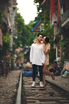 Her kisses make my heart smile. a young couple sharing a romantic moment on the train tracks in the streets of Vietnam
