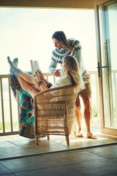 What a lovely lazy long weekend. a young couple reading a book together while relaxing on the balcony