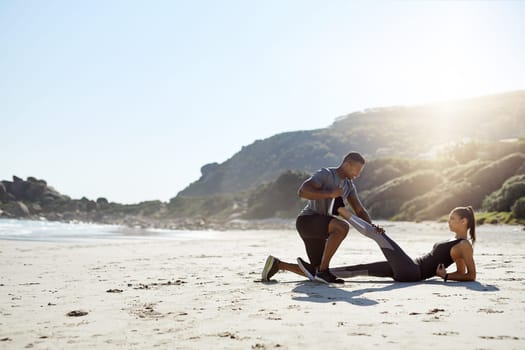 Step one stretch properly. a sporty young couple stretching while exercising along the beach