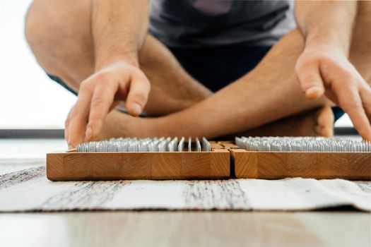 Man exercising yoga meditating and sitting on the floor near sadhu board