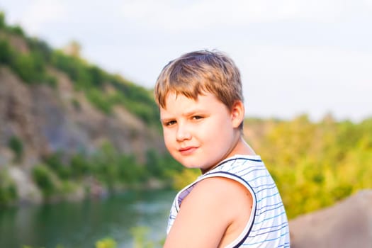 A child sits on the top of a beautiful canyon and looks at the water in it. The bank of the canyon. Portrait of a child.