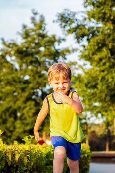 The child spends time in the park, he is very happy. Have fun and enjoy a summer day. Walking and recreation. Portrait of a happy child