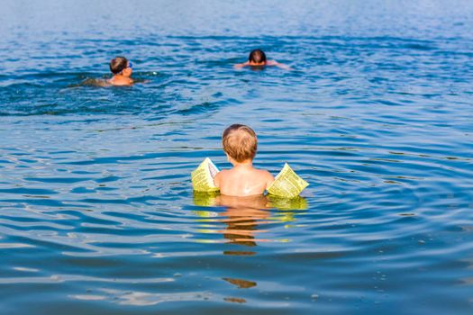 A family, a father and his sons are swimming in the river on a very hot summer day. Swim in reservoirs. A happy family has fun and splashes in the water in the summer. Family on vacation