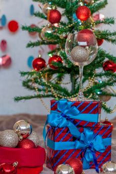 Holiday gifts with blue bows under the tree. Glass with balloons. Christmas and New year. The concept of an advertising banner.